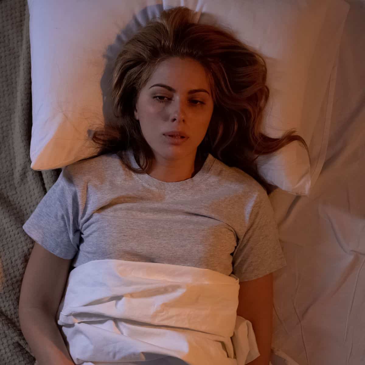A tired woman trying to sleep thinking how tiredness is already affecting her relationship