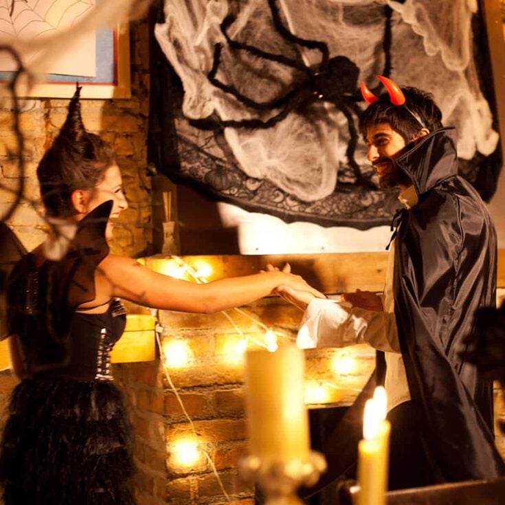 A couple in their Halloween costumes holding hands while having fun after reading these Halloween date ideas