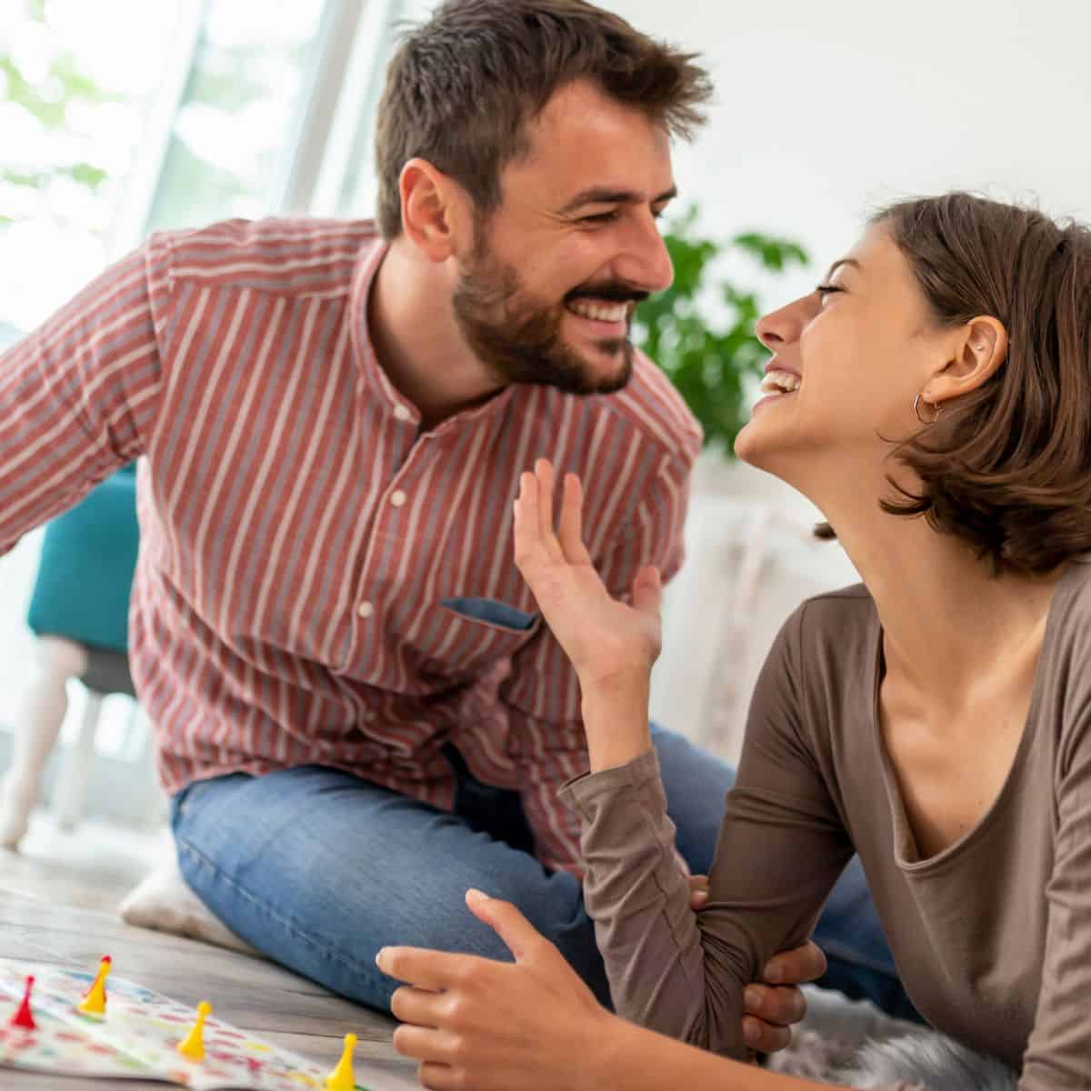 A couple having fun while playing board games after reading these date night games to play at home