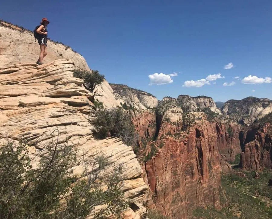 Cheap weekend getaways for couples: Zion National Park. A woman stands on top of a mountain looking into the range on the difference.