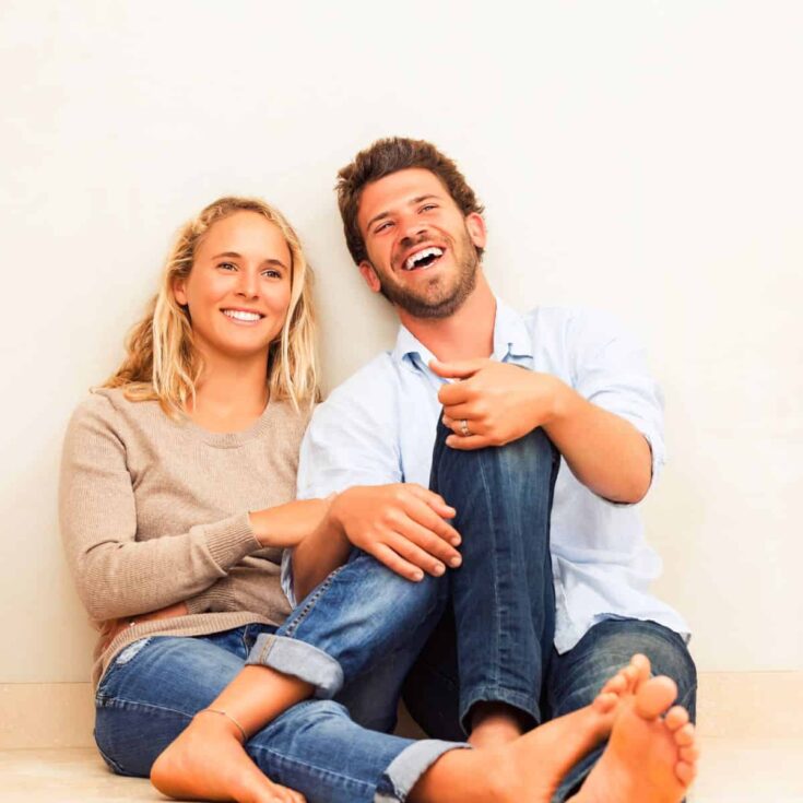 A laughing couple asking each other would you rather questions for couples