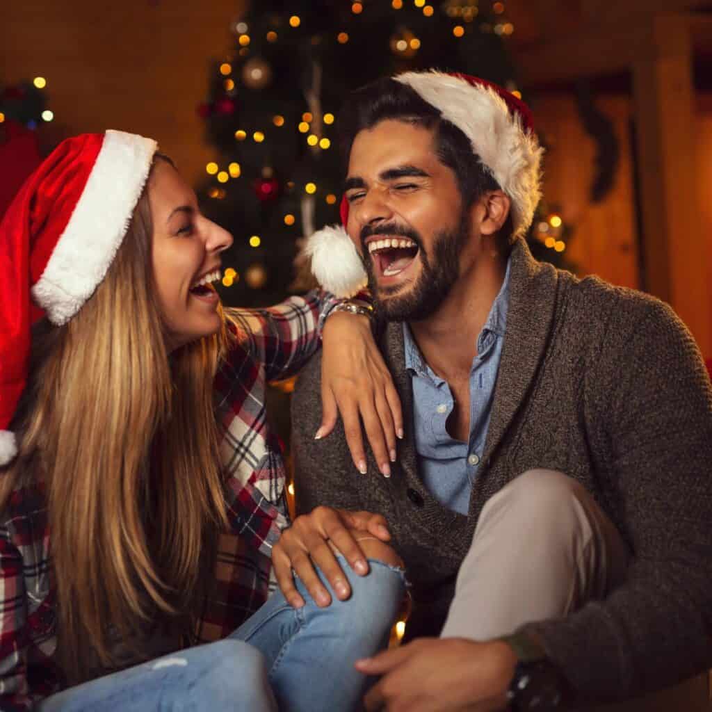 A happy couple laughing together after asking each other these Christmas questions