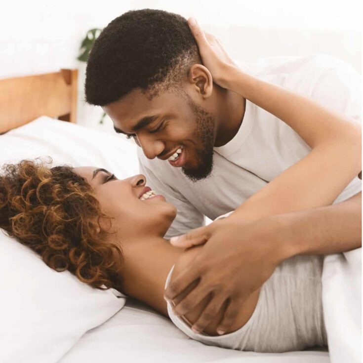 A couple being intimate and playful on the bed after reading these sex board games for couples