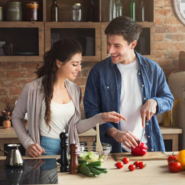 A lovely couple cooking together after reading these date night dinners for date night at home