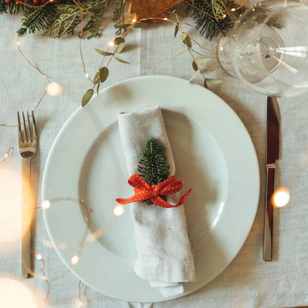 A table set with lovely Christmas ornaments and lights prepared after reading these Christmas dinner menu for two