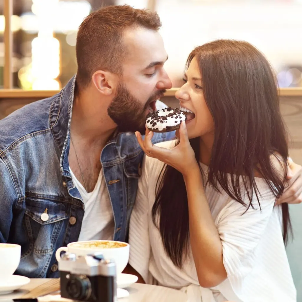 A couple at a restaurant, eating a donut together