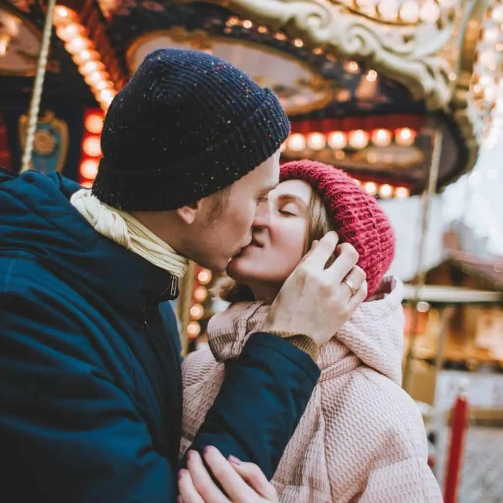 A couple kissing each other at a fair.