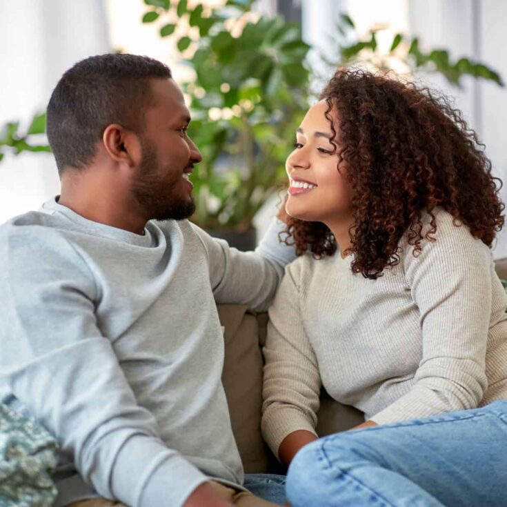 A couple sitting on the couch while asking each other deep questions to ask your partner