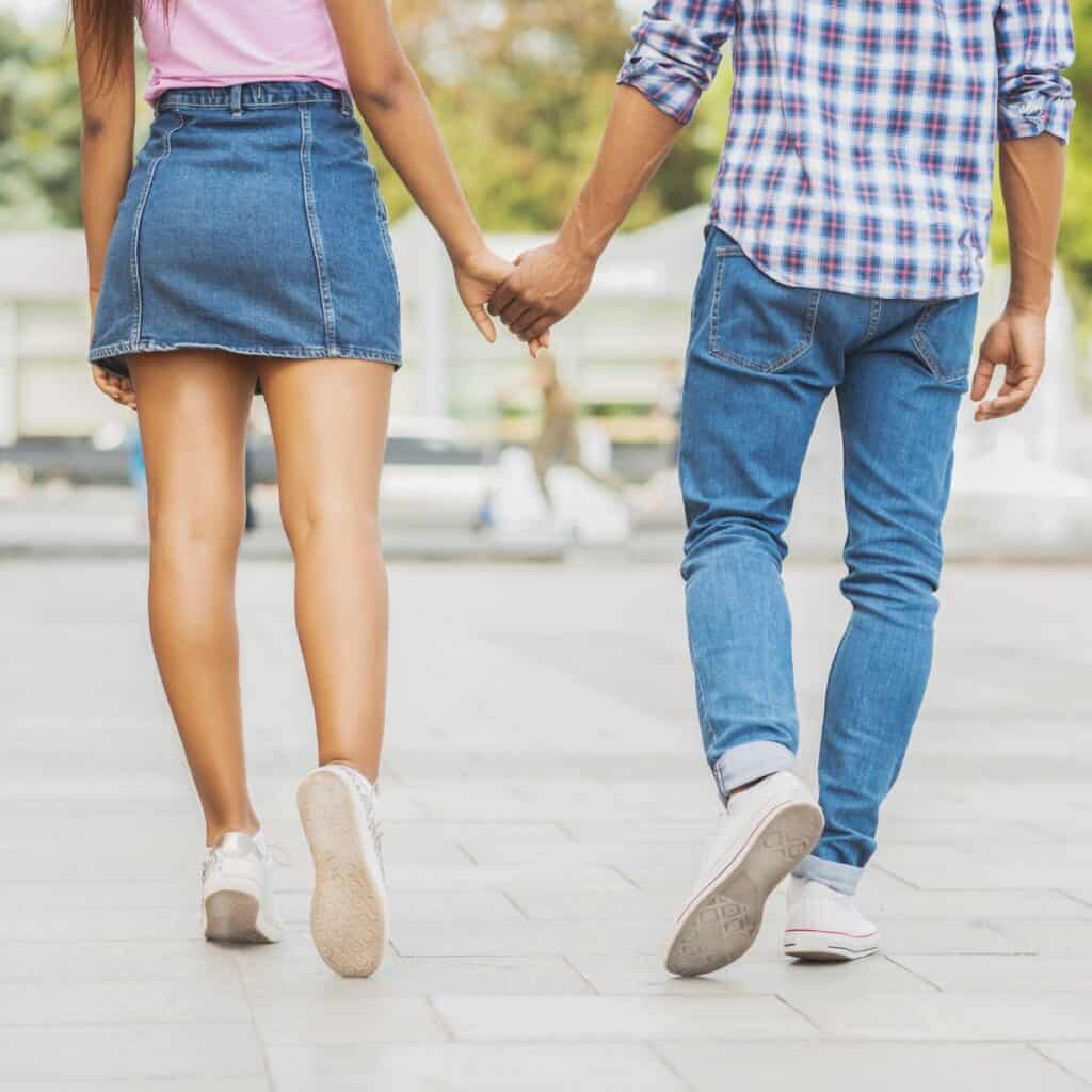 A teen couple holding hands while walking after having their date