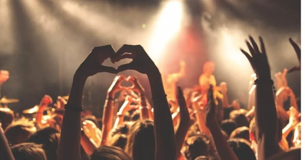 A group of teens' hands waving at a concert: one of the double date ideas for teens.