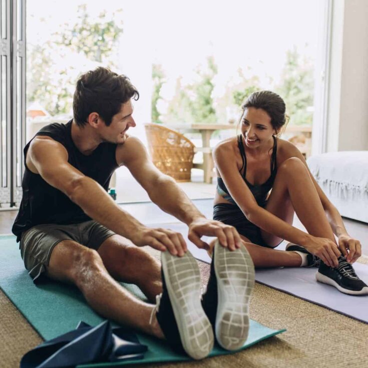 A happy couple exercising in their living room together after reading these fun things for couples to do at home