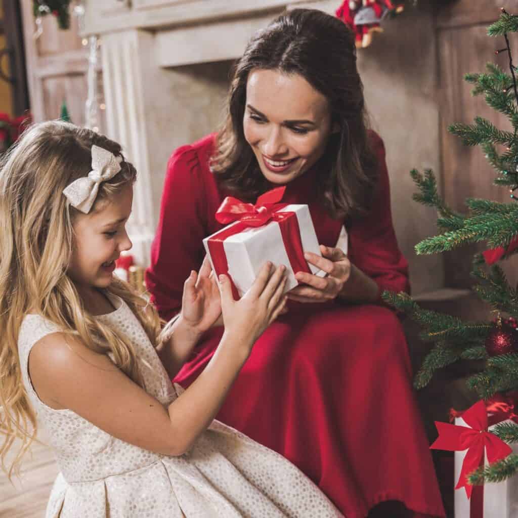 Woman handing her daughter a gift for Christmas