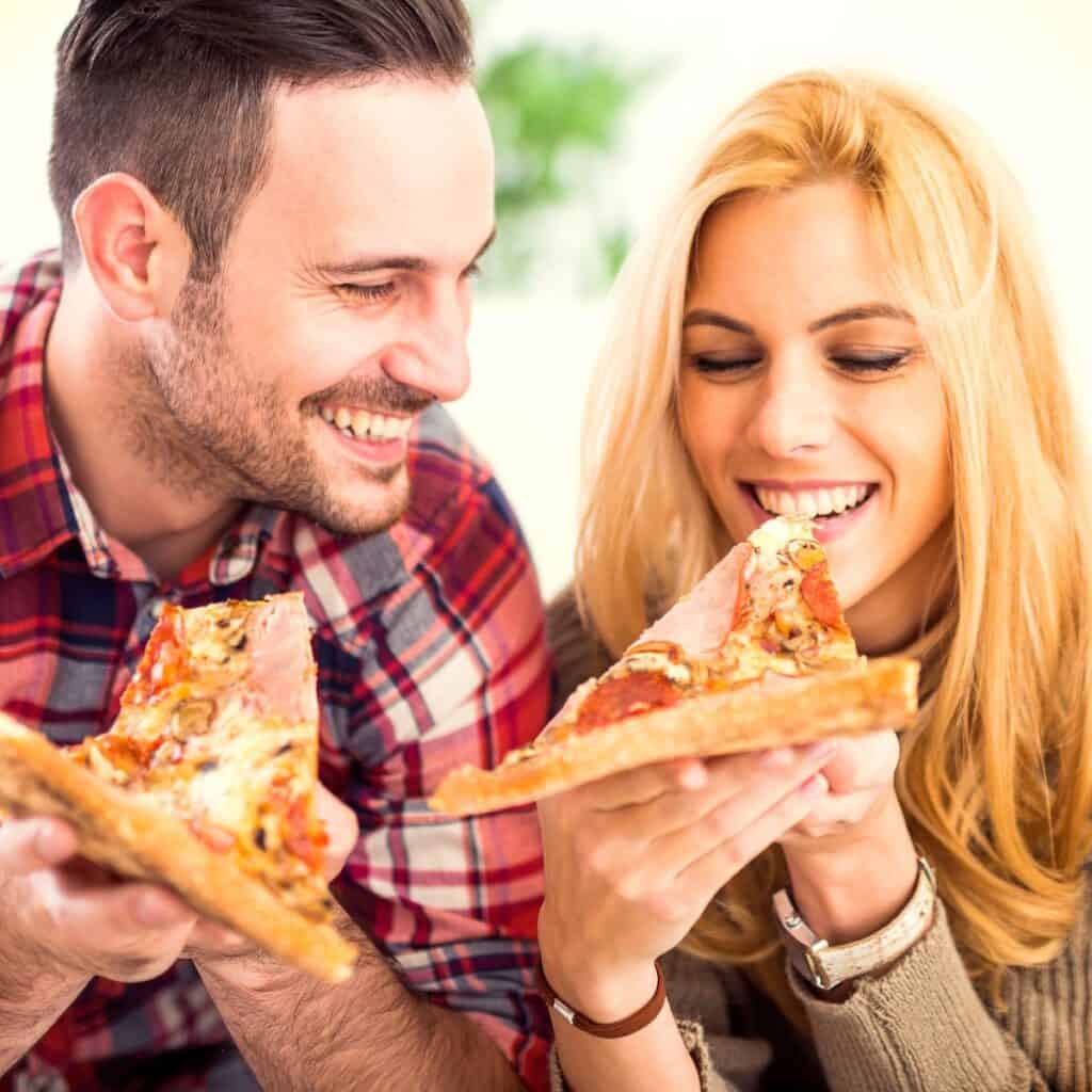 Couple eating a pizza together (challenging each other on who is most likely questions - to eat 2 pizzas in a sitting)