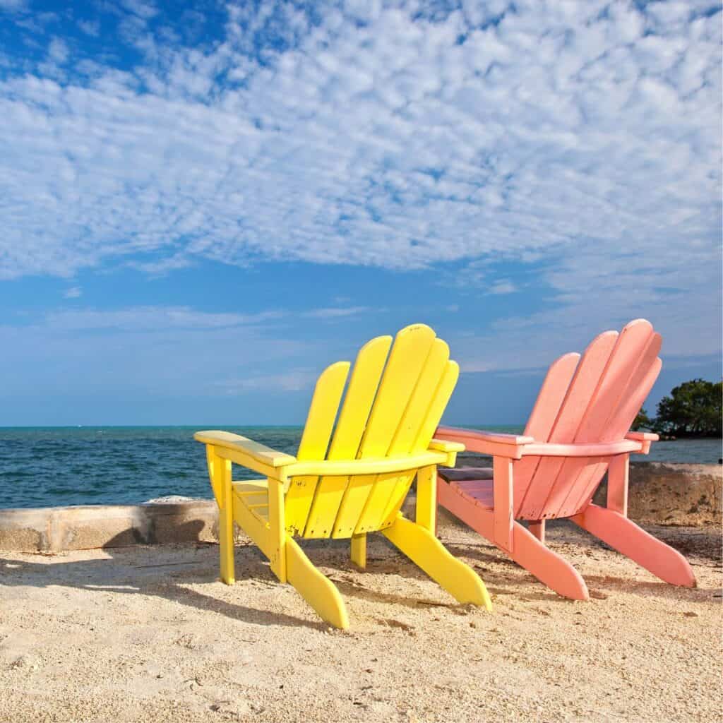 Two Cape Cod chairs in yellow and pink colors on the beach