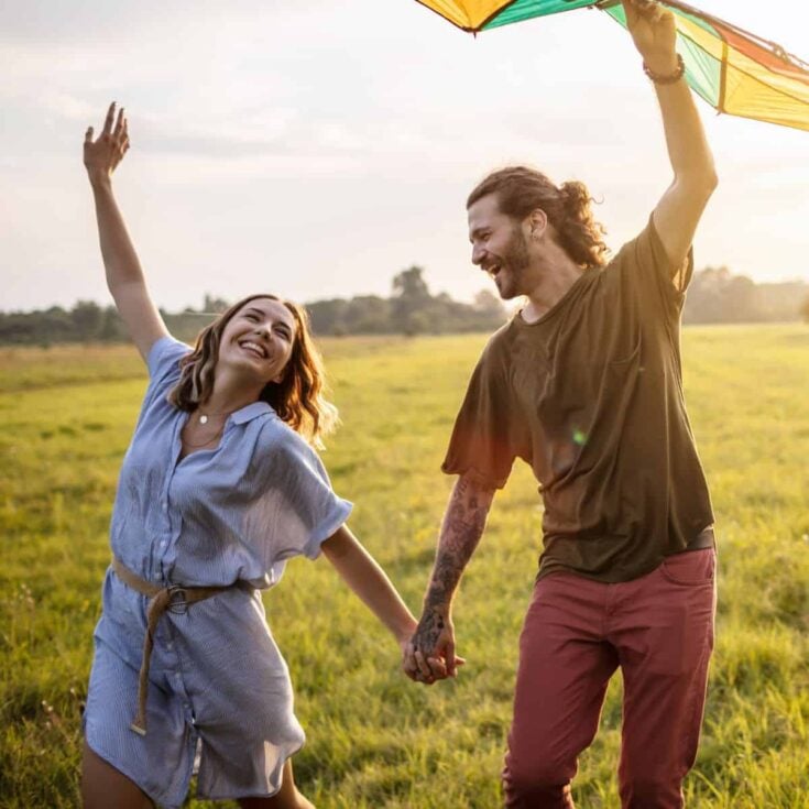 A happy couple running a kite after reading these free date ideas