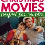 Couple sitting on the couch holding popcorn. They are about to watch one of these romantic Christmas movies. The Christmas tree lights are in the foreground.