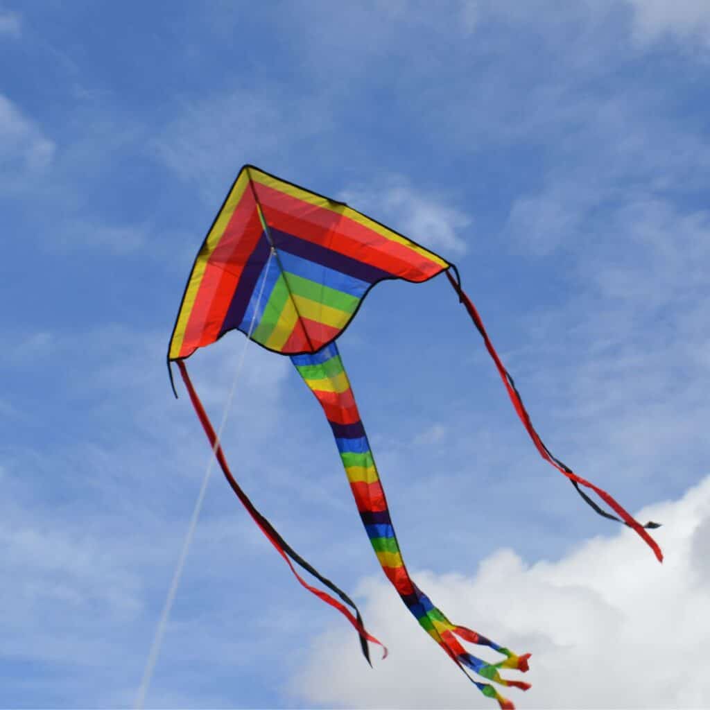 Rainbow colored kite in the blue sky: a cheap Spring date idea
