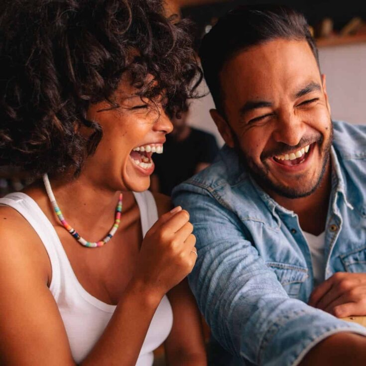 A couple laughing together as they answer this or that questions for couples