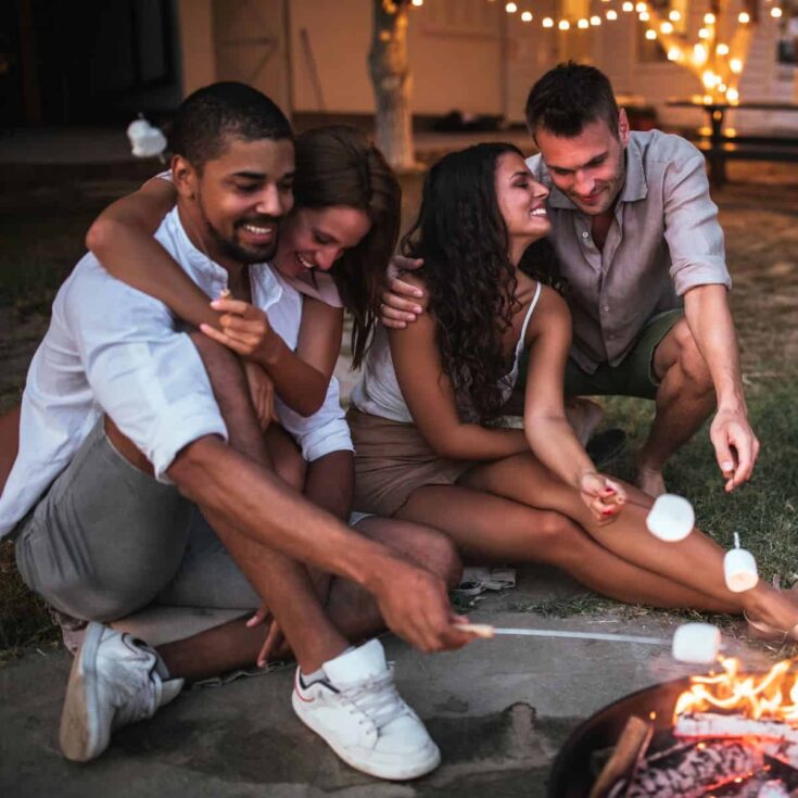 Two couples having fun while roasting marshmallows in a campfire after using these double date ideas