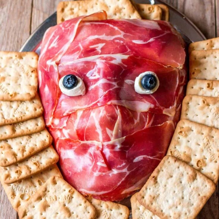 Creepy prosciutto face snack with biscuits on the side, prepared after reading these Halloween snacks date ideas