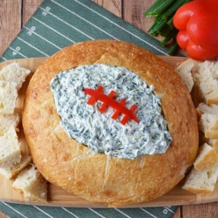 Football shaped bread bowl with spinach dip perfect as Super bowl appetizer