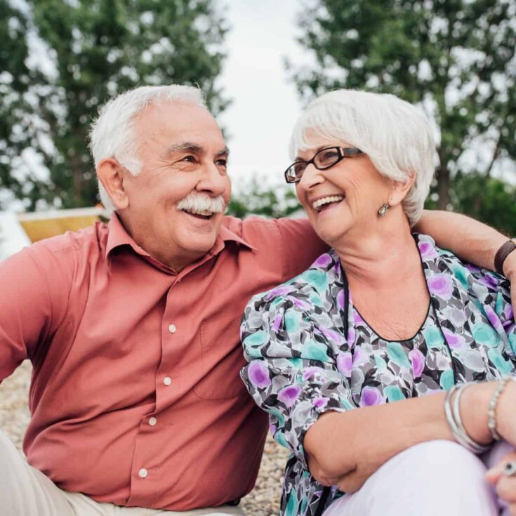 An old couple at a park smiling together, after reading these 50th wedding anniversary quotes