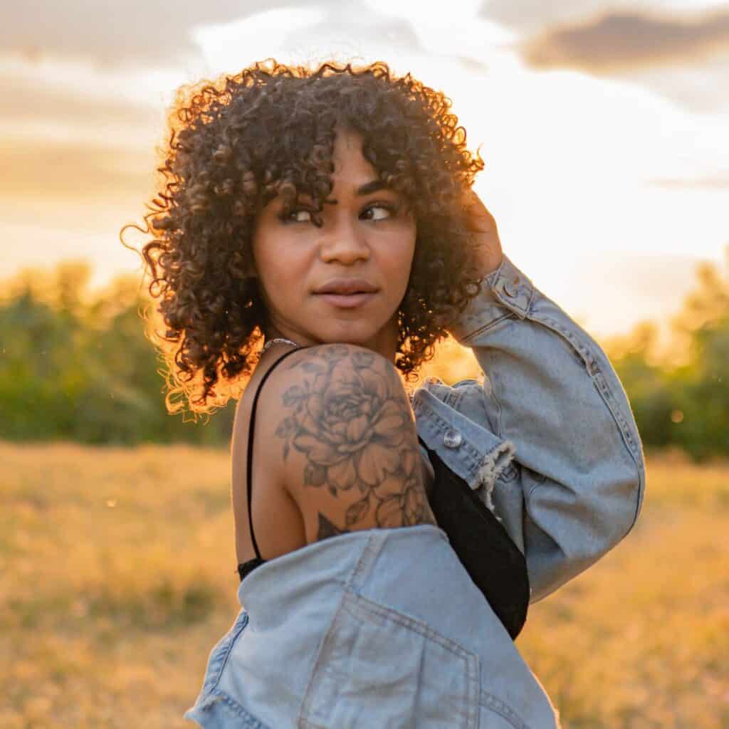 A tattooed woman with a beautiful sunset in the back