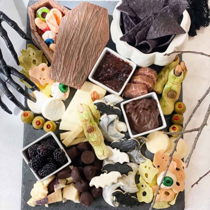 Halloween charcuterie board filled with chocolates, nachos, blackberries, and some creepy Halloween toys