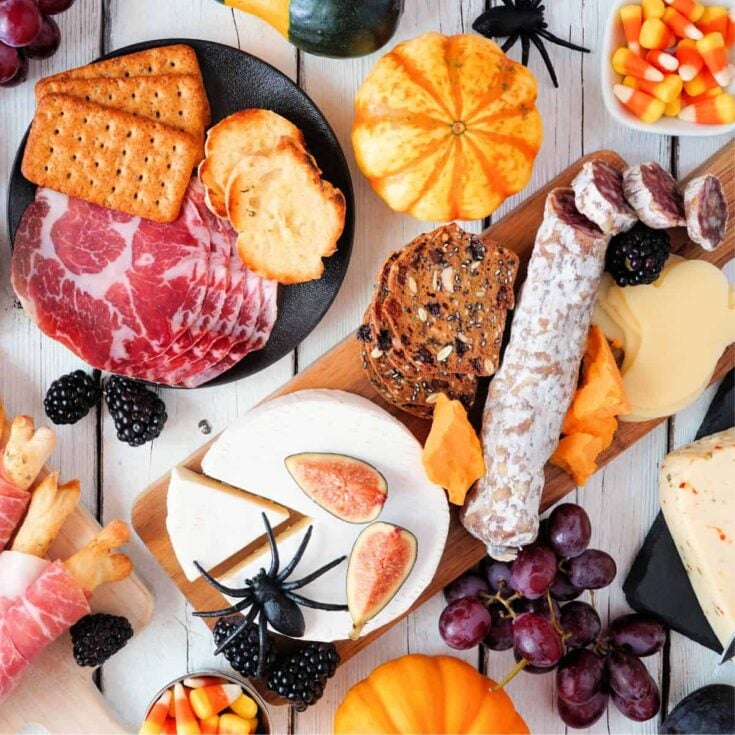 Halloween charcuterie board filled with fruits, cheese, ham, biscuits, and more