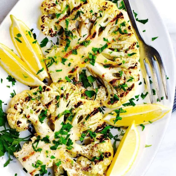 A plate of grilled cauliflower steaks cooked after reading these Summer grilling recipes