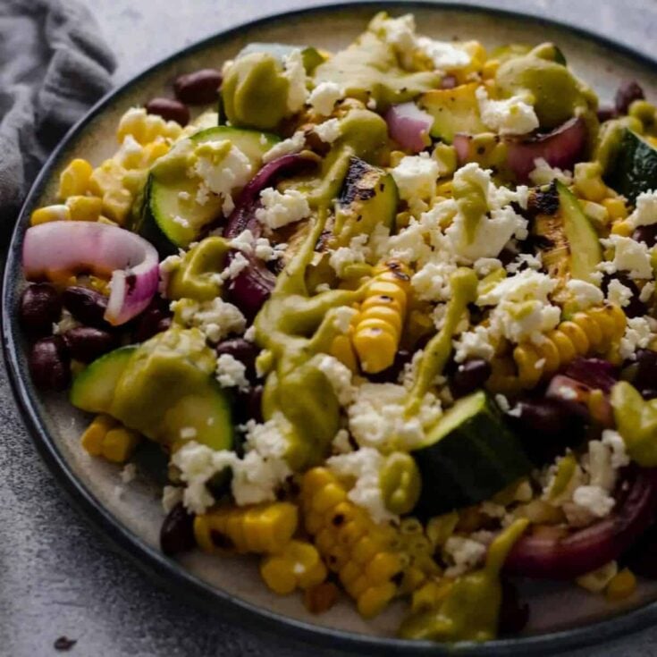 A plate of grilled corn and black bean salad with zucchini, prepared after reading these summer salad recipes
