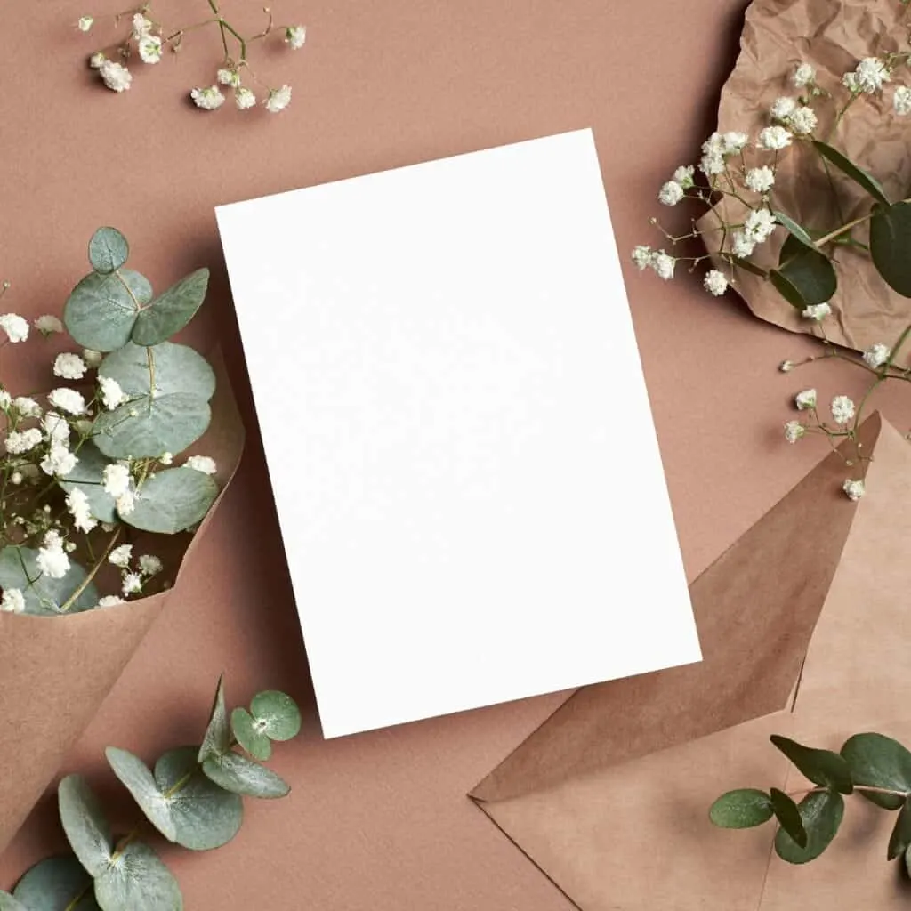 A blank card surrounded by papers, envelopes, and flowers, perfect to write on your wedding wishes for your son and daughter in law