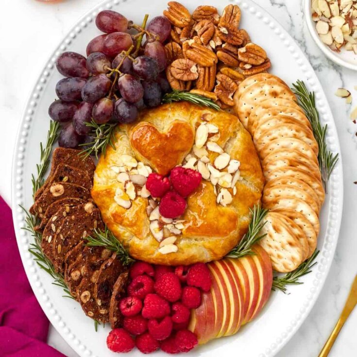 Baked brie en croute filled with biscuits, raspberries, grapes, and more, prepared after reading these Christmas appetizers