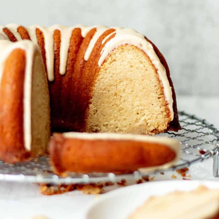 Sliced brown butter rum cake topped with white cream, baked after reading these Christmas Bundt cake recipe