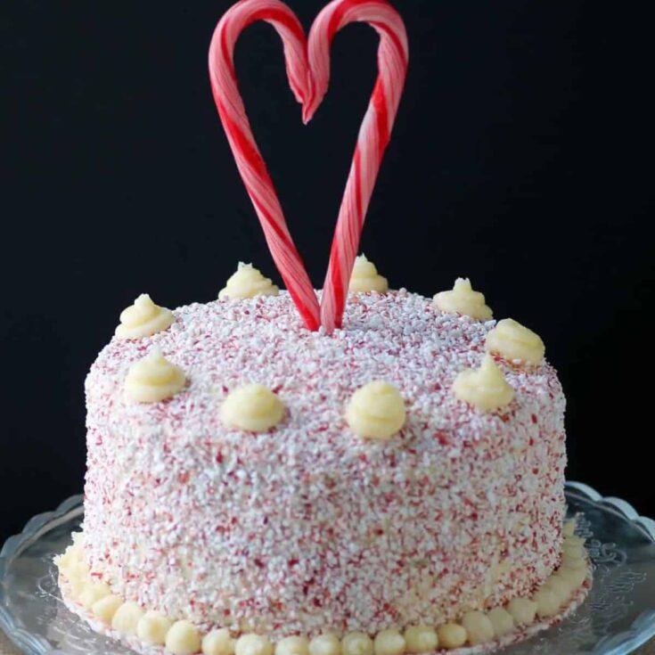 Candy cane cake filled with sprinkles, topped with two candy canes forming a heart, baked after reading these Christmas chocolate cake recipes