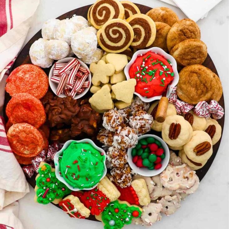 A charcuterie board filled with biscuits, red and green cookies, Christmas tree cookies, and more, prepared after reading these Christmas charcuterie board