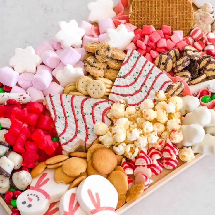 A dessert board filled with biscuits, marshmallows, popcorn, cookies, and more, prepared after reading these Christmas charcuterie board