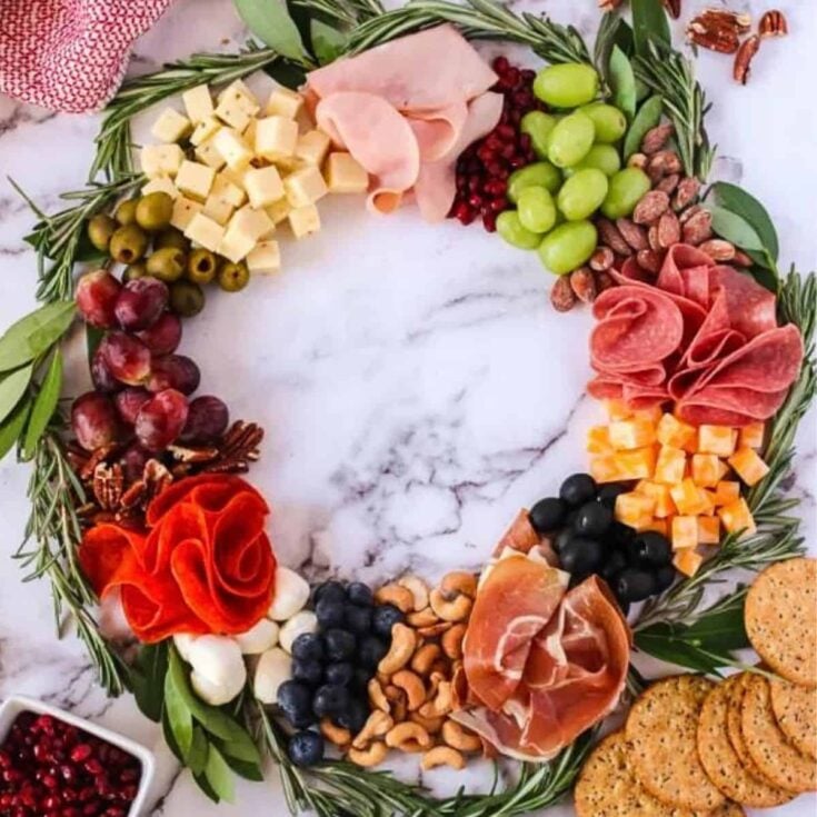A wreath shaped charcuterie board filled with cheese, ham, berries and more, prepared after reading these Christmas charcuterie board