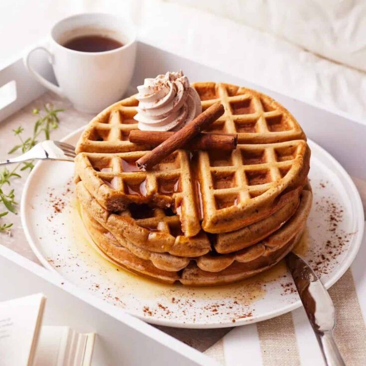 A plate of cinnamon waffles with cinnamon whipped cream prepared after reading these Fall breakfast ideas