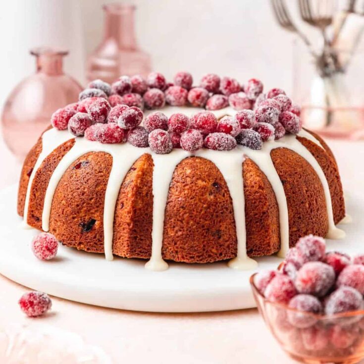 Cranberry cake, topped with white cream and berries, baked after reading these Christmas Bundt cake recipe