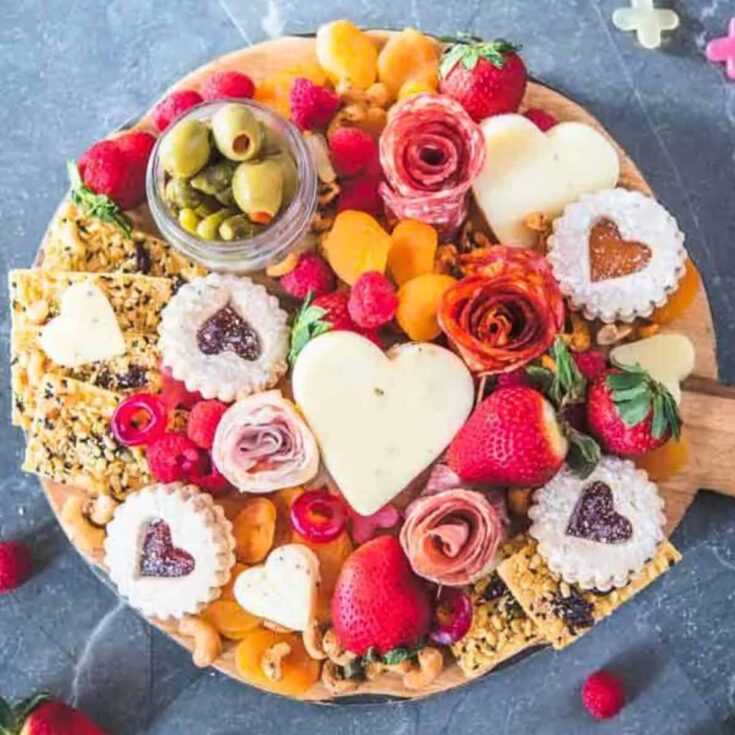 A Valentines charcuterie board filled with salami roses, cheese, chocolates, and more