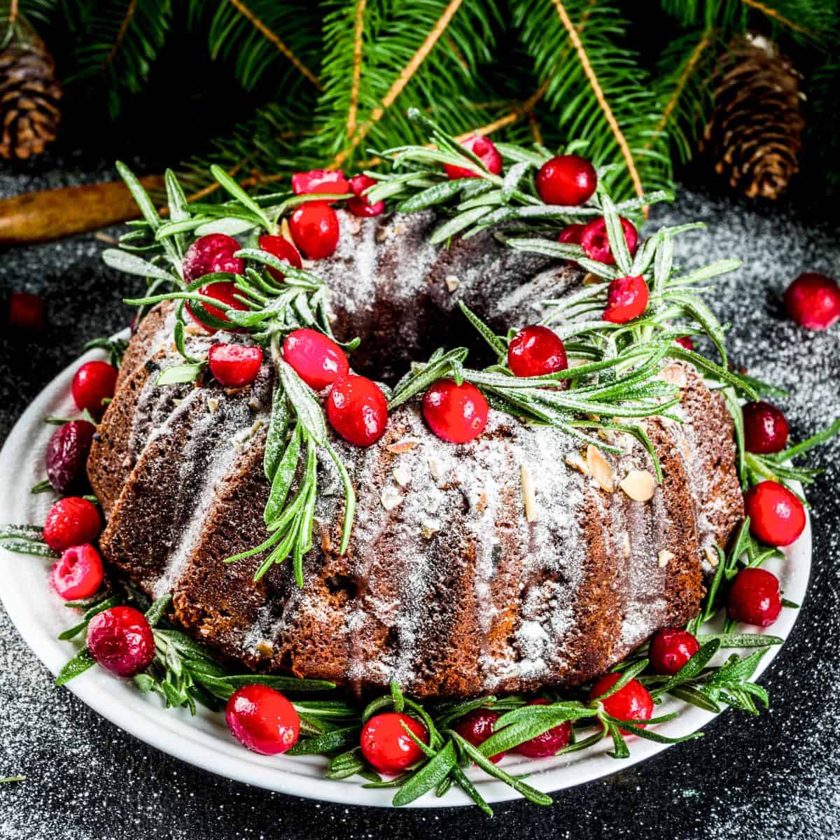 A bundt cake topped with cherries and powdered sugar, baked after reading these Christmas bundt cake recipes