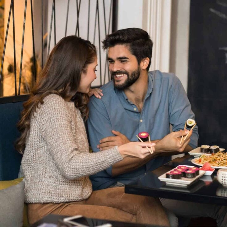 A happy couple eating on a sushi restaurant after reading these lunch date ideas for busy couples
