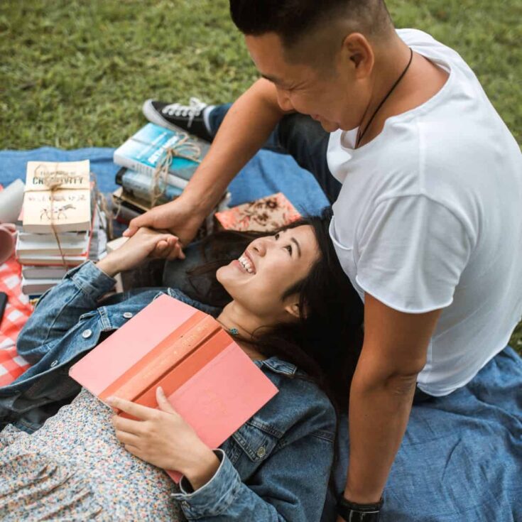 A couple bonding over books together during a picnic, after reading these date ideas for book lovers