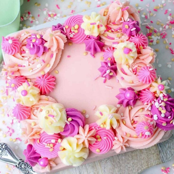 Vanilla cake with buttercream frosting topped with icing and sprinkles, baked after reading these Valentines day cake recipes