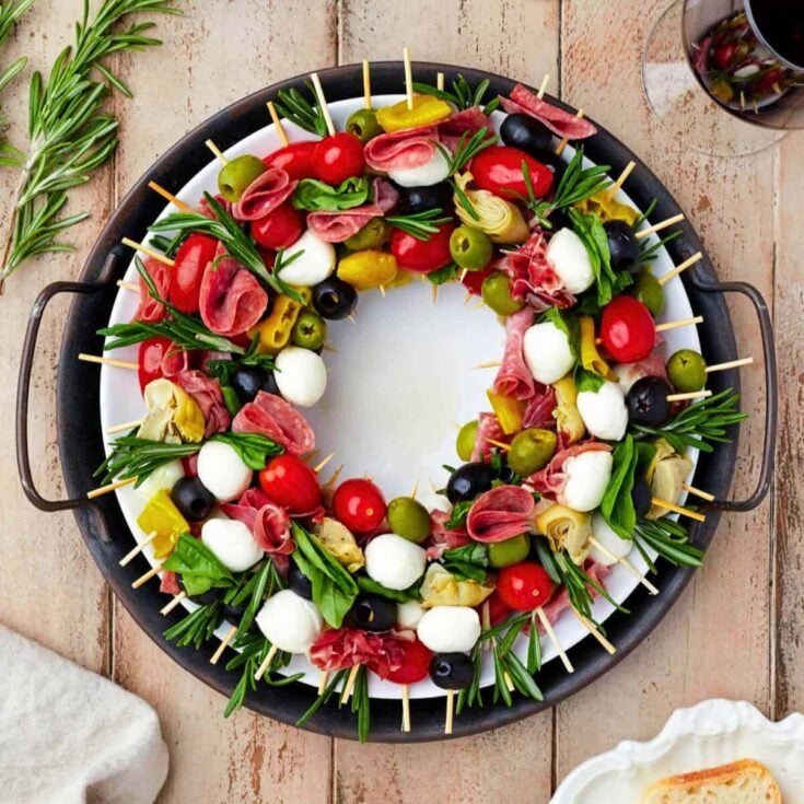 A wreath shaped charcuterie board surrounded by skewers prepared after reading these Christmas charcuterie board