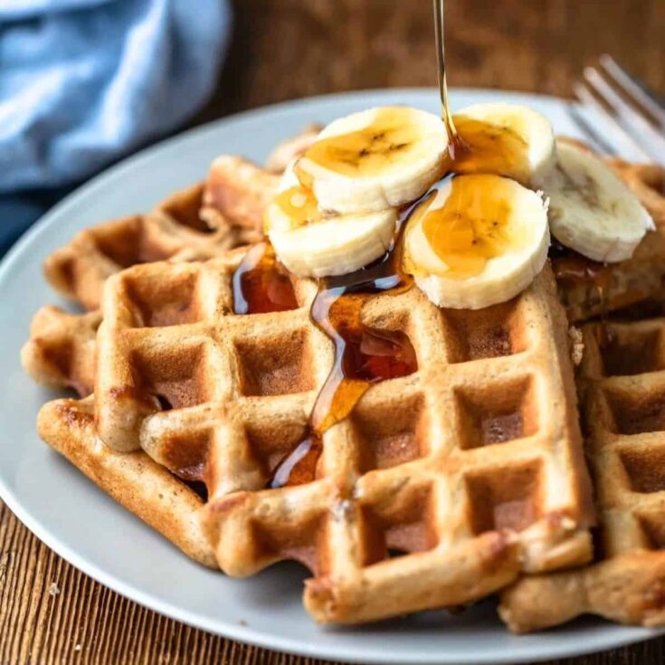Banana waffles, topped with banana slices and maple syrup, made after reading these Wonderful waffle recipes
