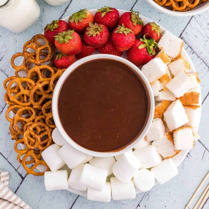 Chocolate fondue bowl surrounded by pretzels, bread slices, strawberries, and marshmallows, prepared after reading these Easy fondue recipes