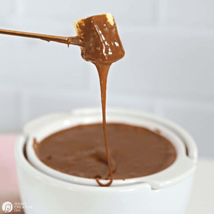 A marshmallow being dipped on a chocolate fondue, prepared after reading these Easy fondue recipes