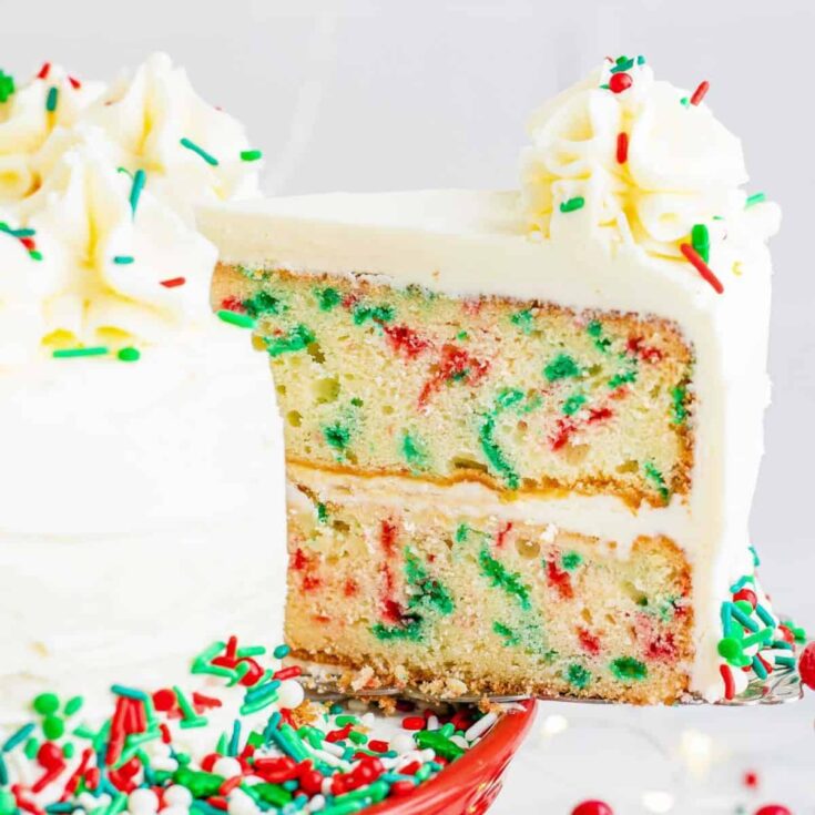 A slice of Christmas layer cake filled with red and green sprinkles baked after reading these Christmas cake recipes